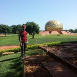 Mikey stands smiling in front of the Matrimandir in Auroville