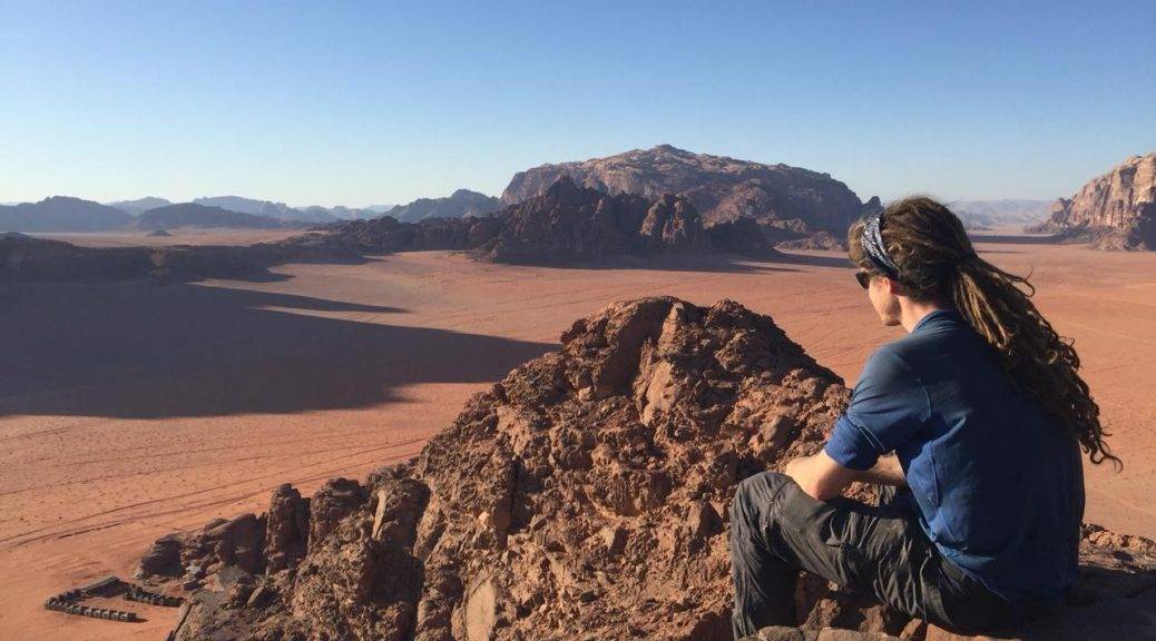 Mikey sits atop a sandstone mounain overlooking their bedouin camp in Wadi Rum