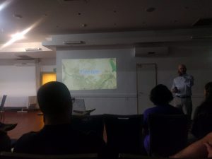 A man giving a presentation to a bunch of sleepy participants shakes his finger at the audience. Behind him the words "Zionism" are projected onto the wall.